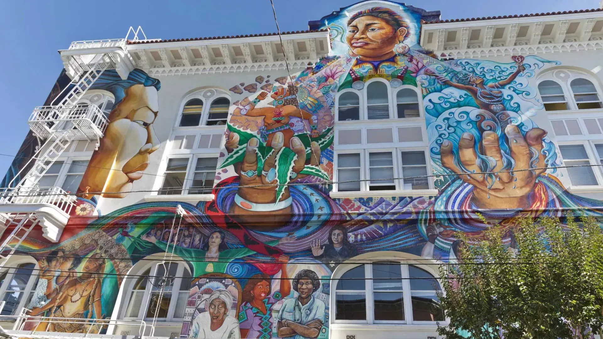 Un mural colorido y de gran escala cubre el costado del Edificio de Mujeres en el Distrito de la Misión de San Francisco.