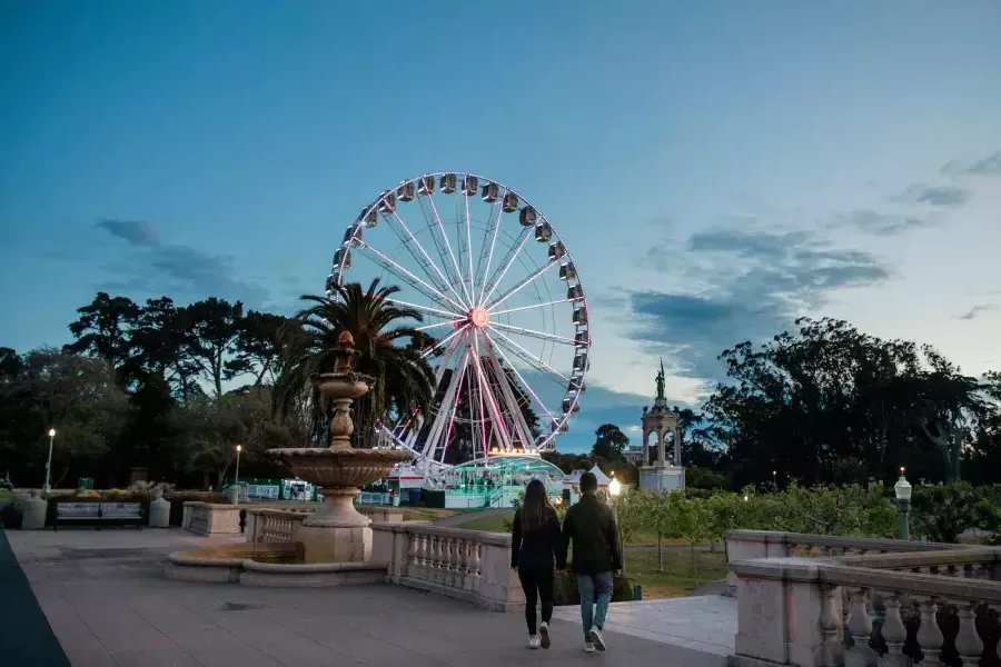 Ein Paar geht in der Abenddämmerung zum SkyStar-Riesenrad.